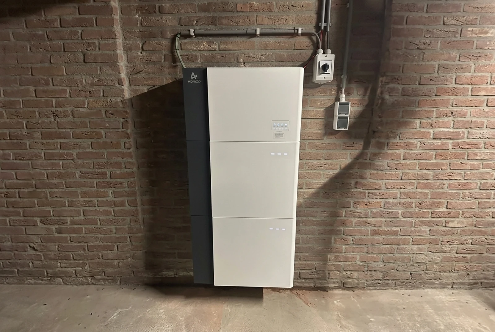 Geïnstalleerde AlphaESS-thuisbatterij aan een bakstenen binnenmuur.