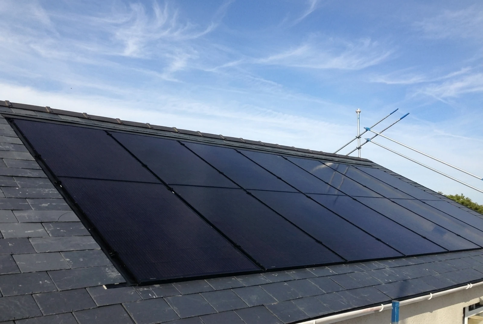 Paneelveld van zwarte JA Solar-zonnepanelen op een leistenen dak.
